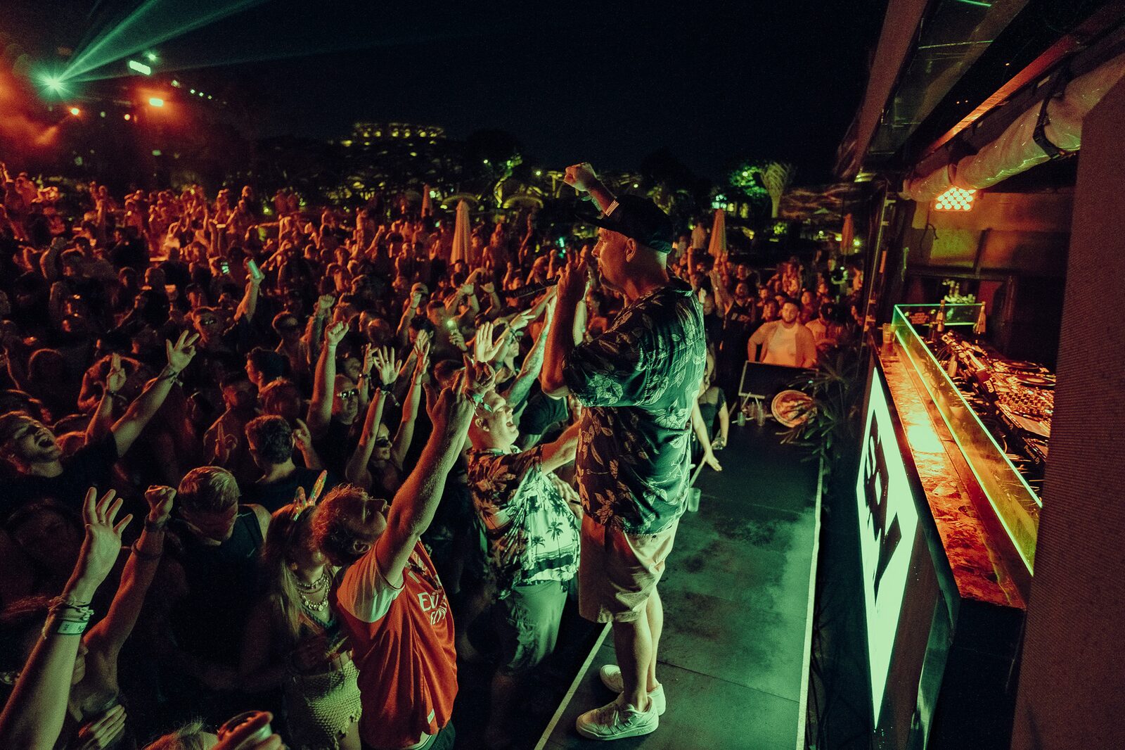 DJ performing at LOCUS Bali 2025, with crowd cheering and golden lighting